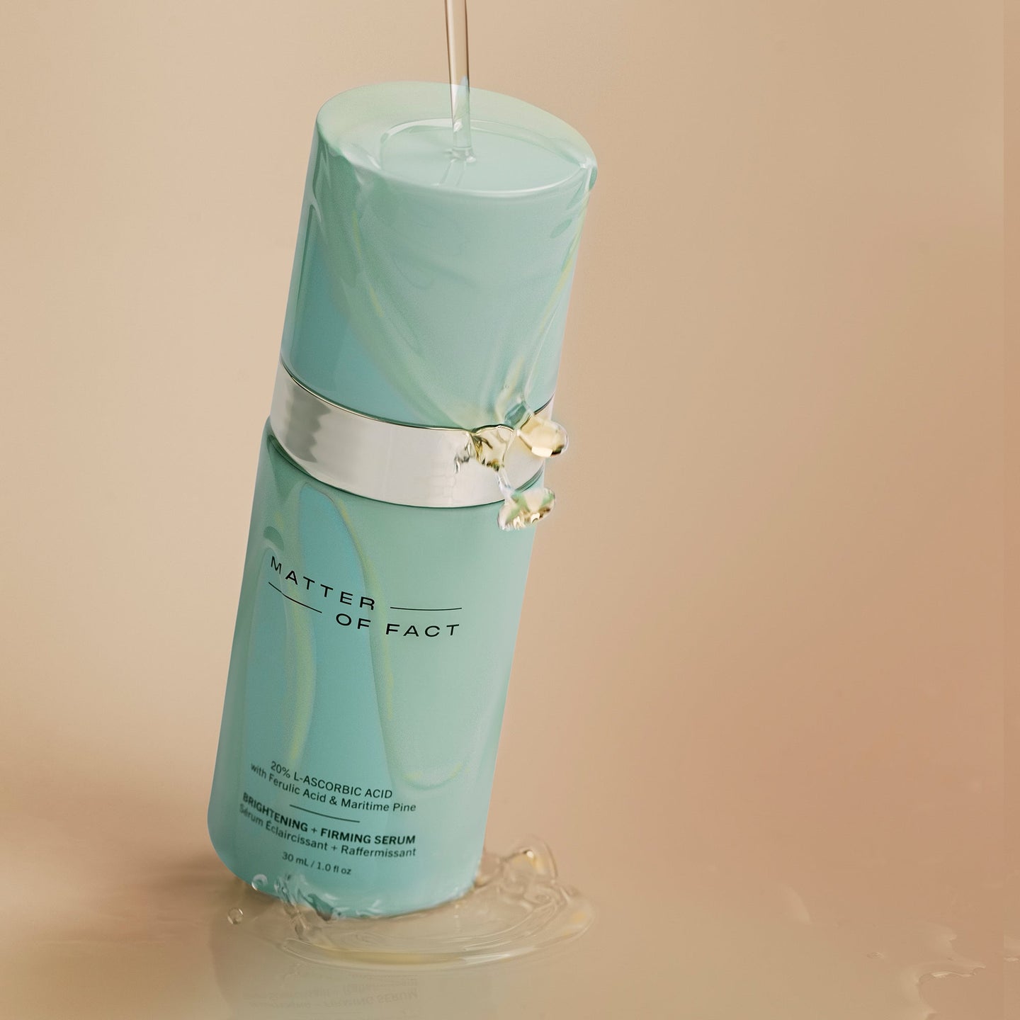 MATTER OF FACT SKINCARE BRIGHTENING AND FIRMING SERUM product vessel in a beige background with product liquid falling on the vessel